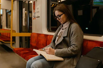 A young woman focusing on her studies while traveling on a quiet train ride.